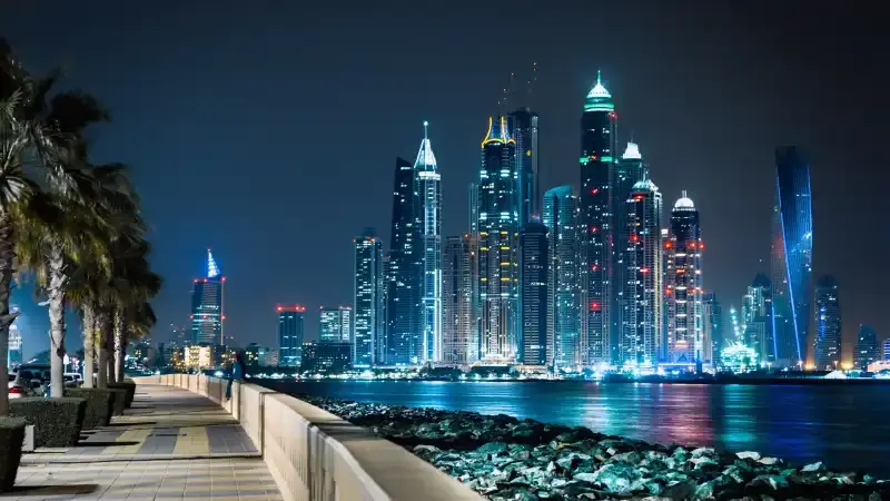 أبراج دبي المضيئة تنعكس على المياه، مشهد يعكس روعة السفر إلى دبي في عطلة عيد الفطر.
