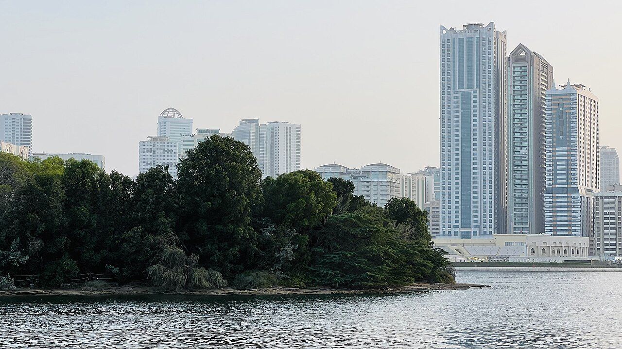 Al Noor Island in Sharjah surrounded by greenery and water with the city skyline in the background