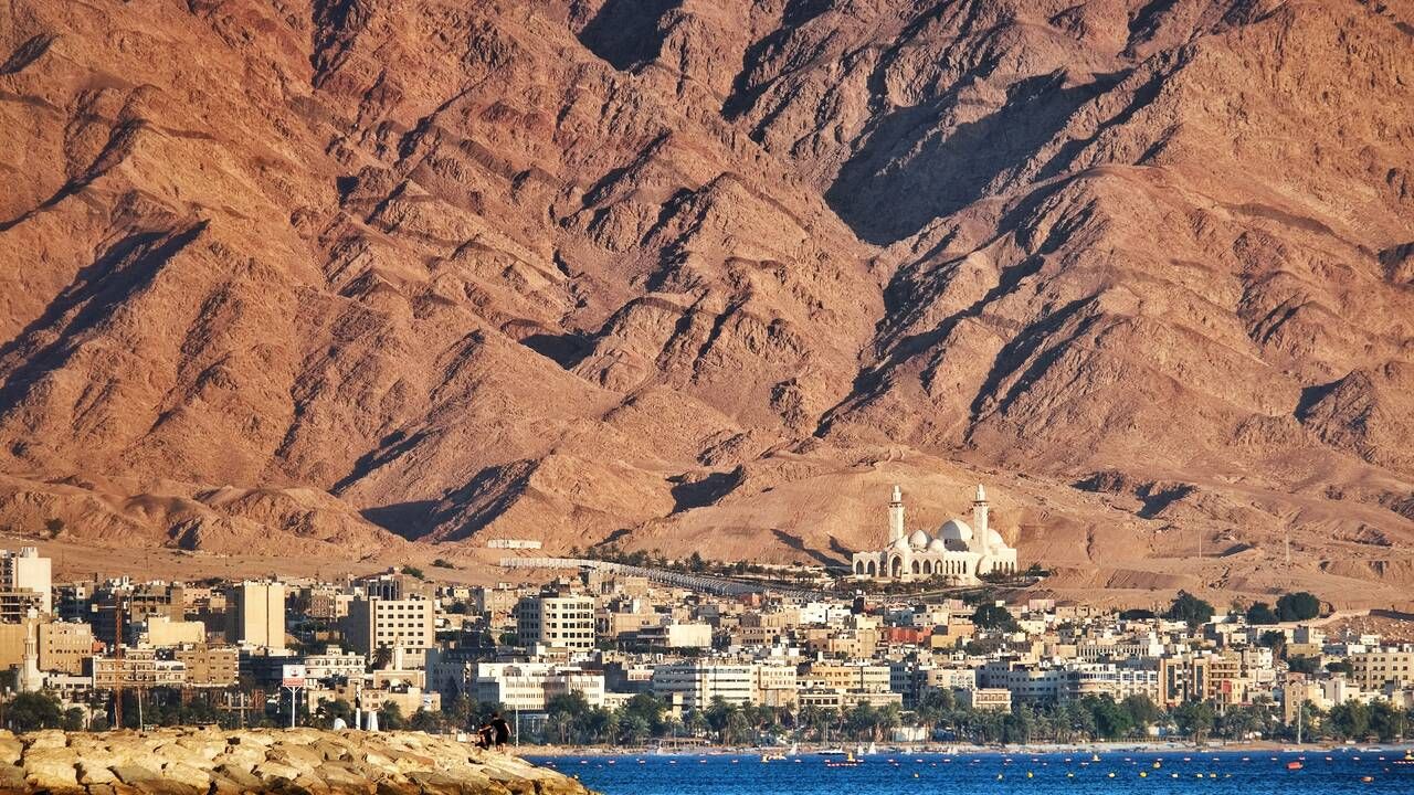 Wide view of Aqaba on the Red Sea with the city, mosque and red mountains in Jordan
