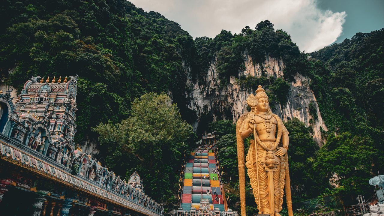 Wide view of Batu Caves with the golden Lord Murugan statue and colorful rainbow steps in Malaysia