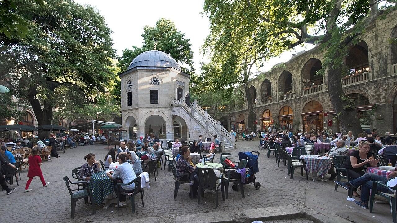 Wide view of the historic Koza Han silk market courtyard with Ottoman arcades and visitors in Bursa, Turkey