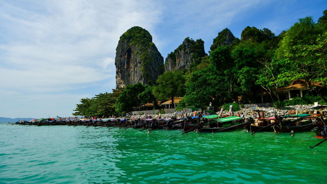 Wide view of Railay Beach in Krabi with limestone cliffs, turquoise water and traditional long-tail boats