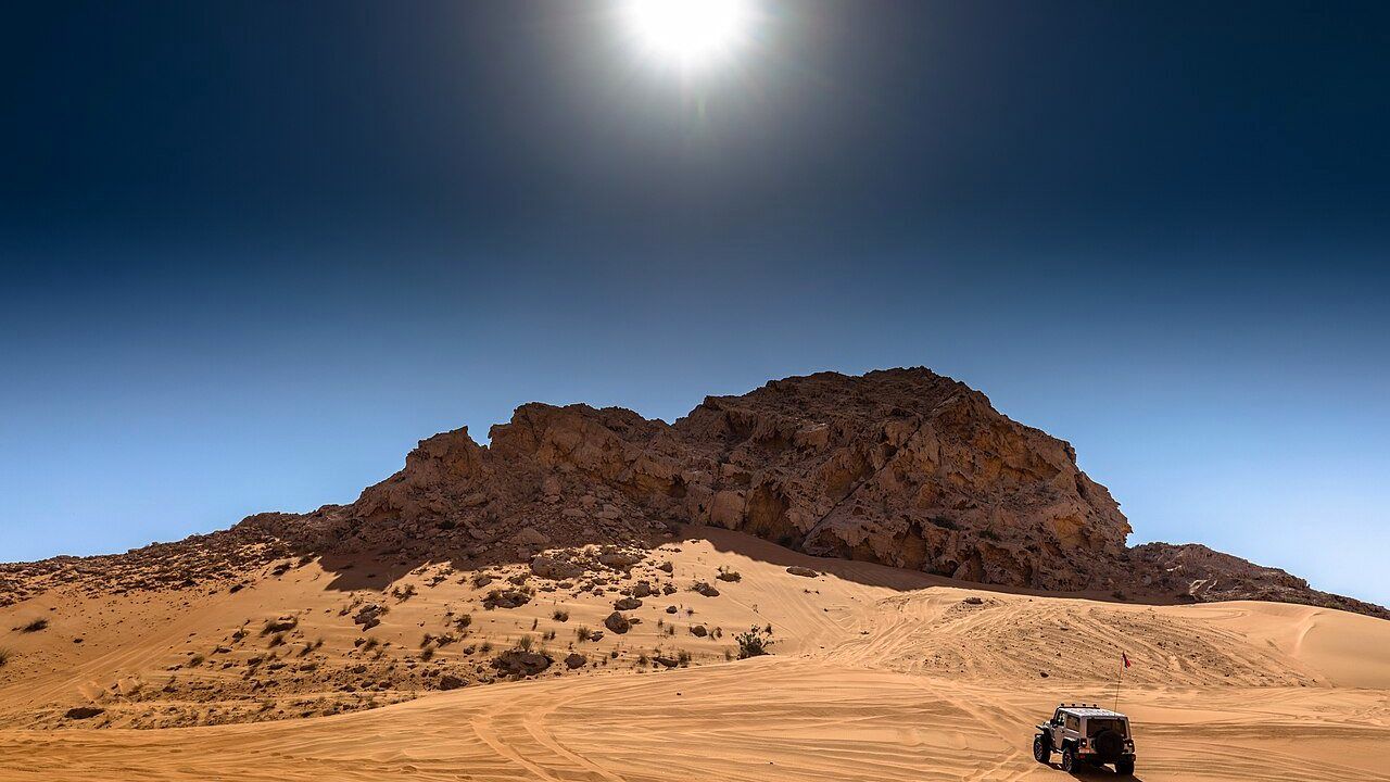 Fossil Rock and desert landscape in Mleiha, Sharjah with an off-road vehicle on the sand dunes