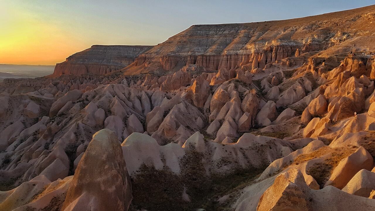 Wide sunset view of Red Valley and Rose Valley rock formations in Cappadocia, Türkiye