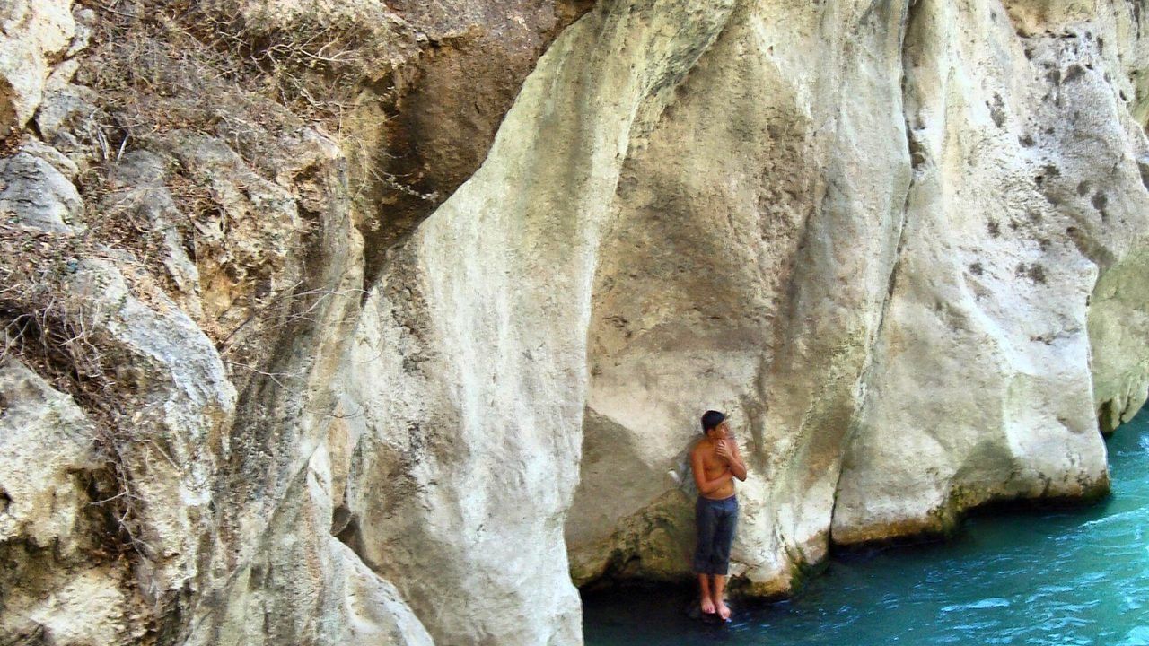 Visitors walking through the narrow rocky passage and clear water of Saklikent Canyon