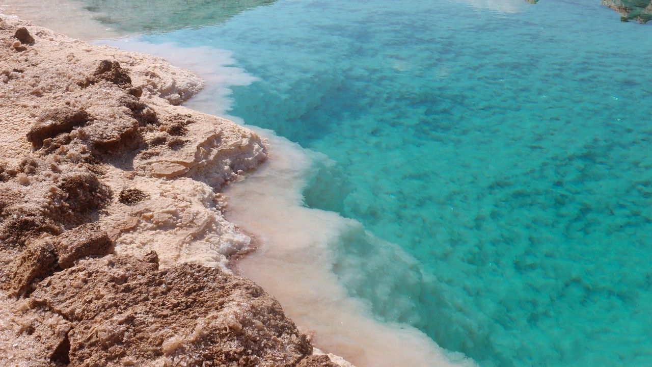 Turquoise salt lake surrounded by natural salt formations in Siwa Oasis, Egypt