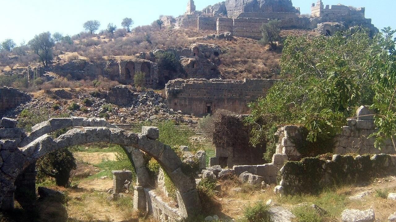 Wide view of ancient stone ruins and an arched gateway at Tlos Ancient City